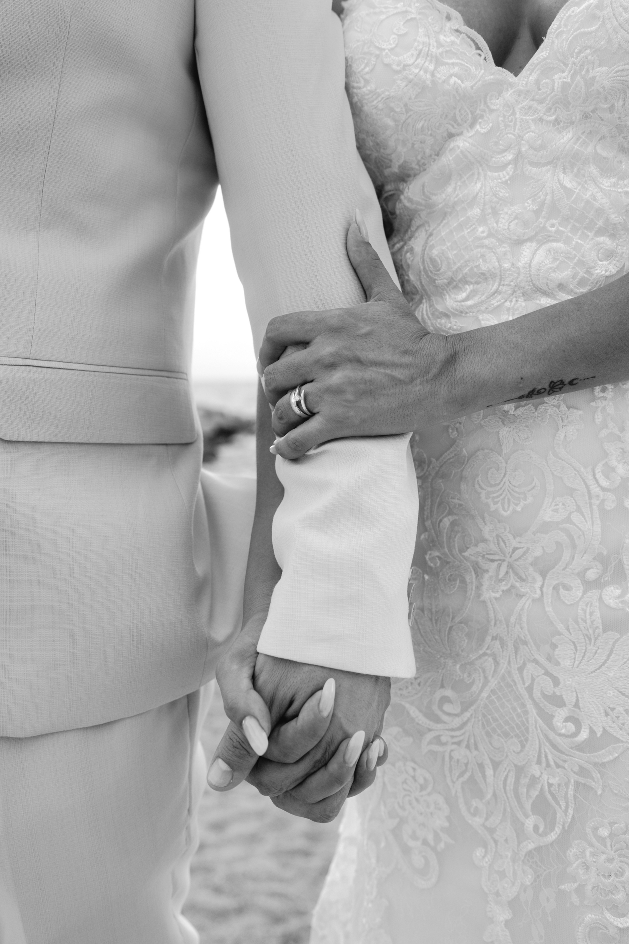 Bride and groom holding hands, black and white detail